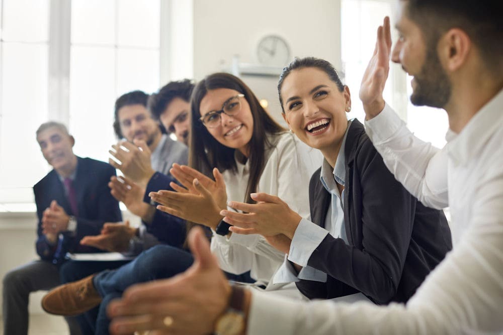 Group of people applauding person holding up one hand