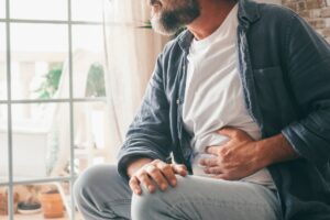 Hand of mature guy holding abdomen suffering from stomach pain