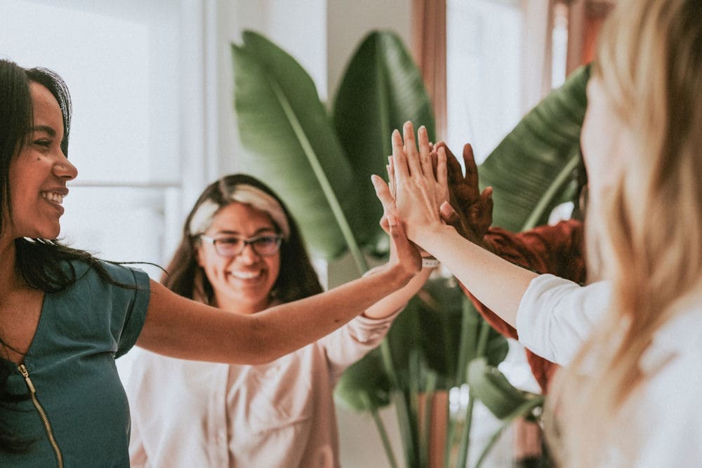dangers-of-white-knuckle-sobriety Women in support group doing group high-five.