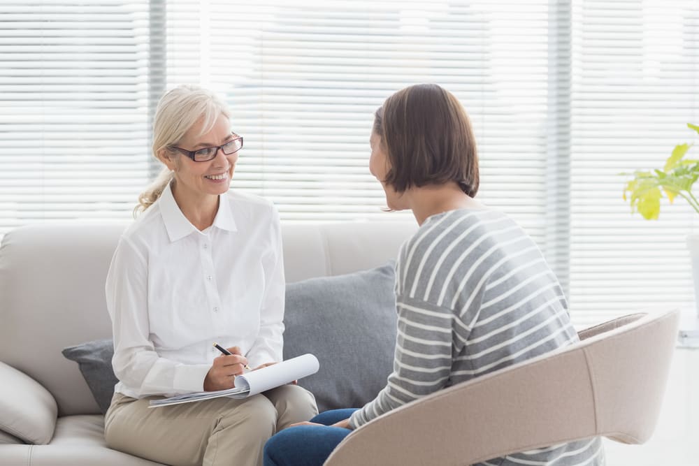smiling therapist with woman patient for addiction and mental health treatment