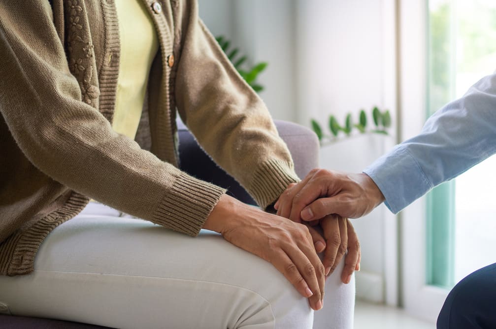 Woman and man sitting on couch two people holding hands showing sign sincere feelings, compassion and empathy