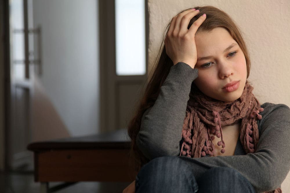 Young woman holding head in frustration about her gambling addiction.