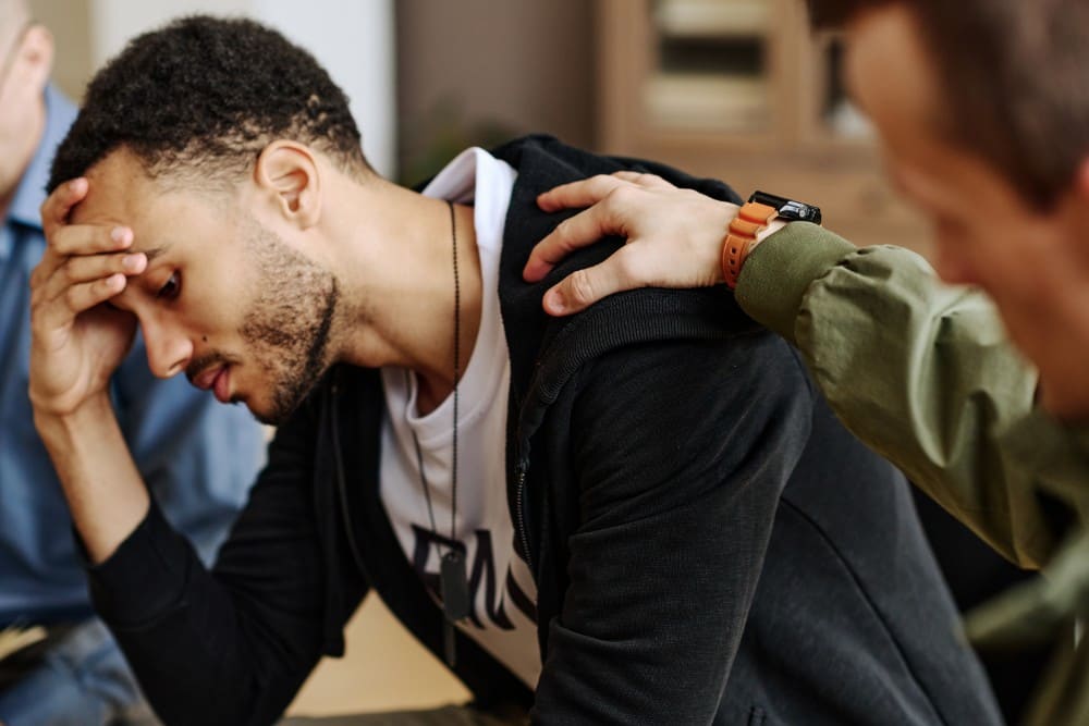 a man holding friends shoulder whom showing symptoms of PTSD and substance abuse