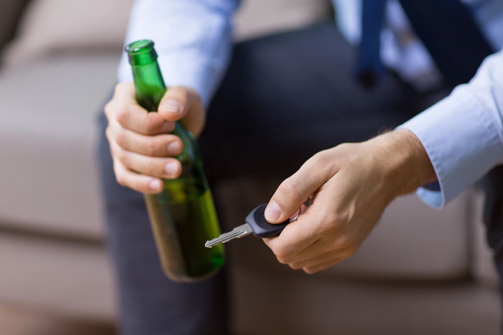 Man holding car keys and alcohol – Risks of Drinking and Driving