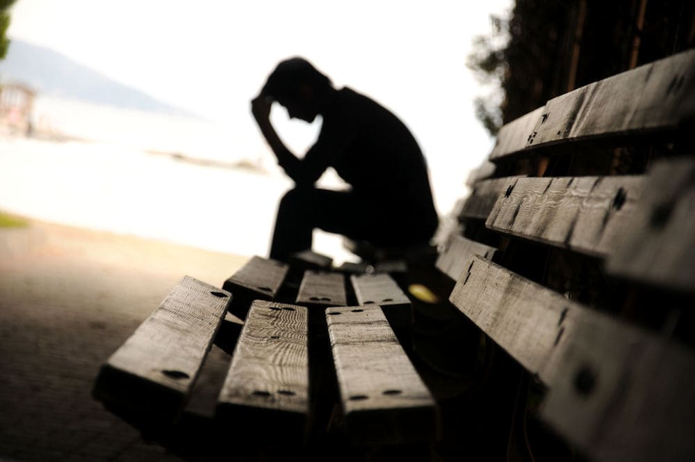 Man sitting on a bench, troubled by gambling addiction