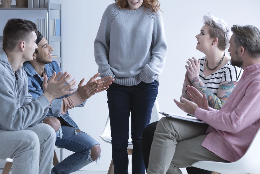 a group of addicted patients encouraging one of their members to participate in group sessions
