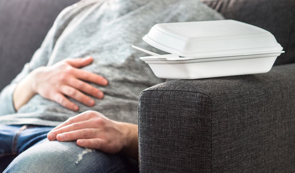 Person resting with hands on stomach after overeating