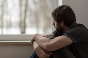 man showing symptoms of depression as he blankly stares at a window
