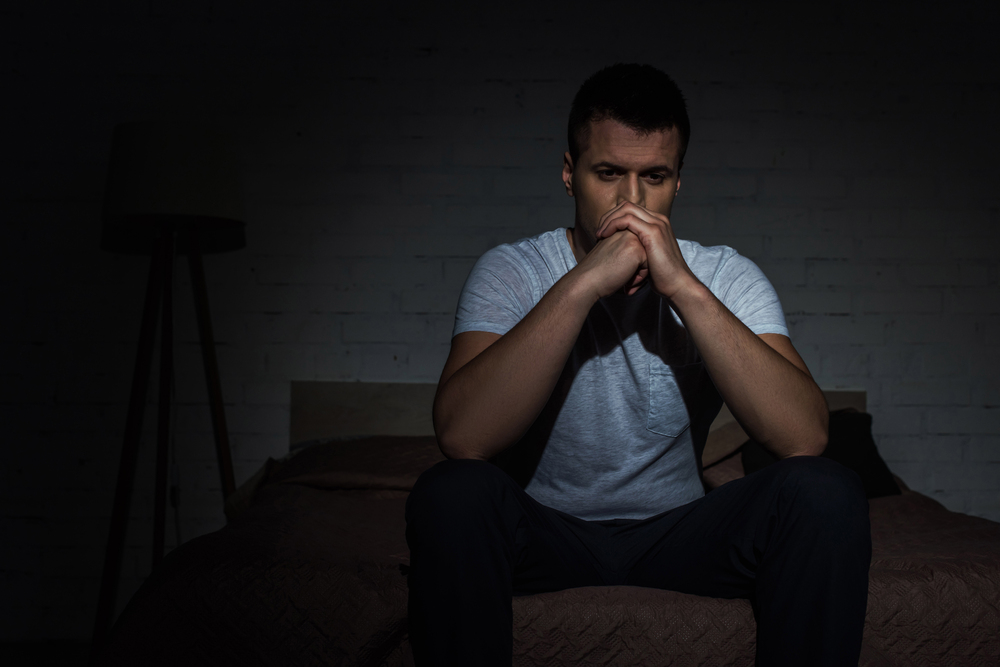 A man sitting alone in emotional distress, struggling with grief and addiction