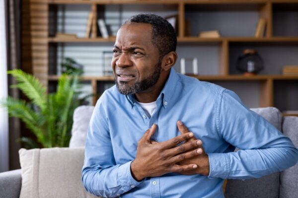 Man experiencing chest pain sitting on a sofa in a home setting