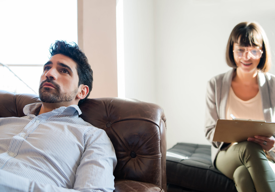 a man lying on the couch while the therapist is doing an evaluation