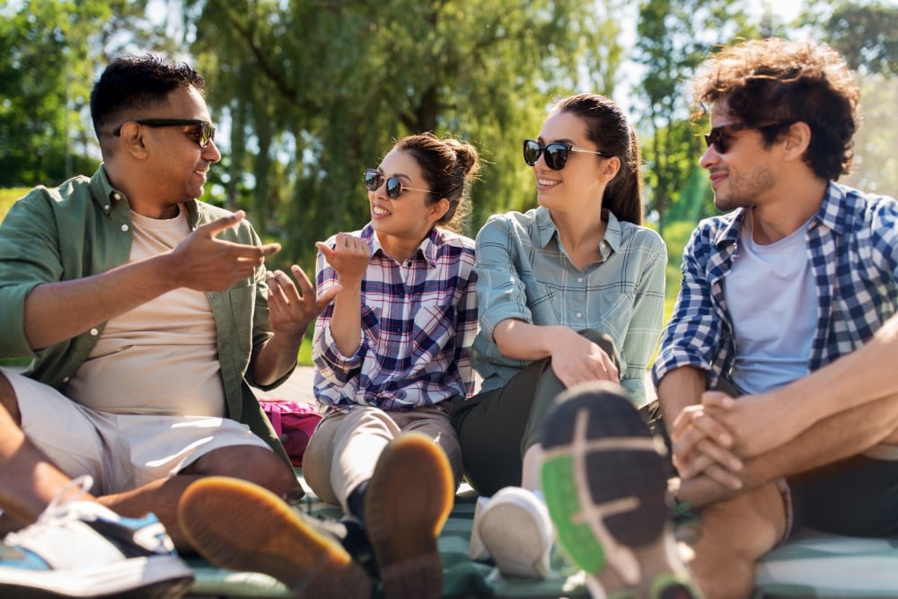group of people sitting on the grass in conversation and staying sober during holiday