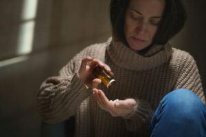 Woman holding a bottle of pills, highlighting signs of Adderall addiction