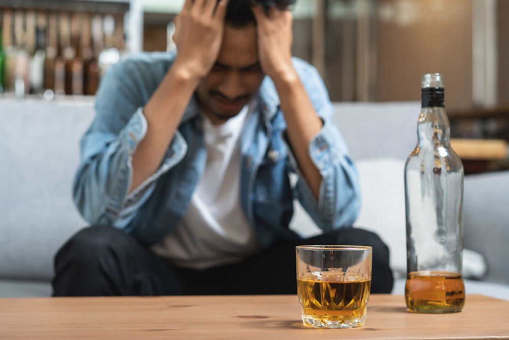 Former soldier agonizing over glass of straight whiskey poured on table in front of him