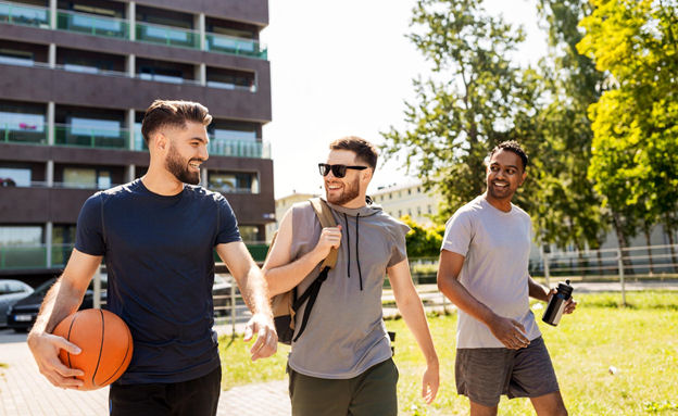 Three men walking along a quad after playing basketball