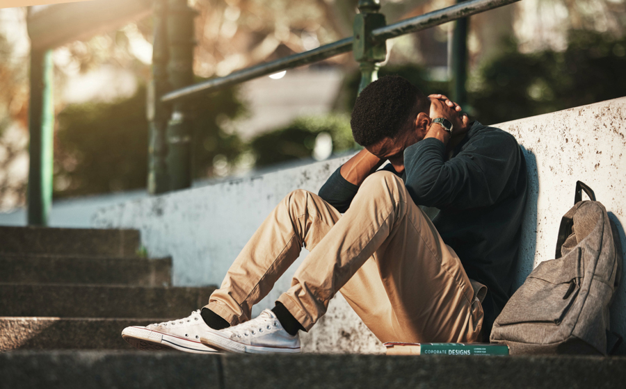 Young man holding back of neck while sitting on concrete steps