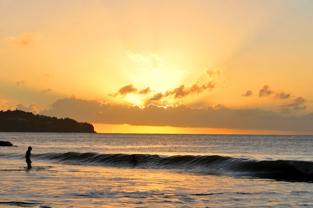 Wide shot of two people playing in the ocean as the sun set