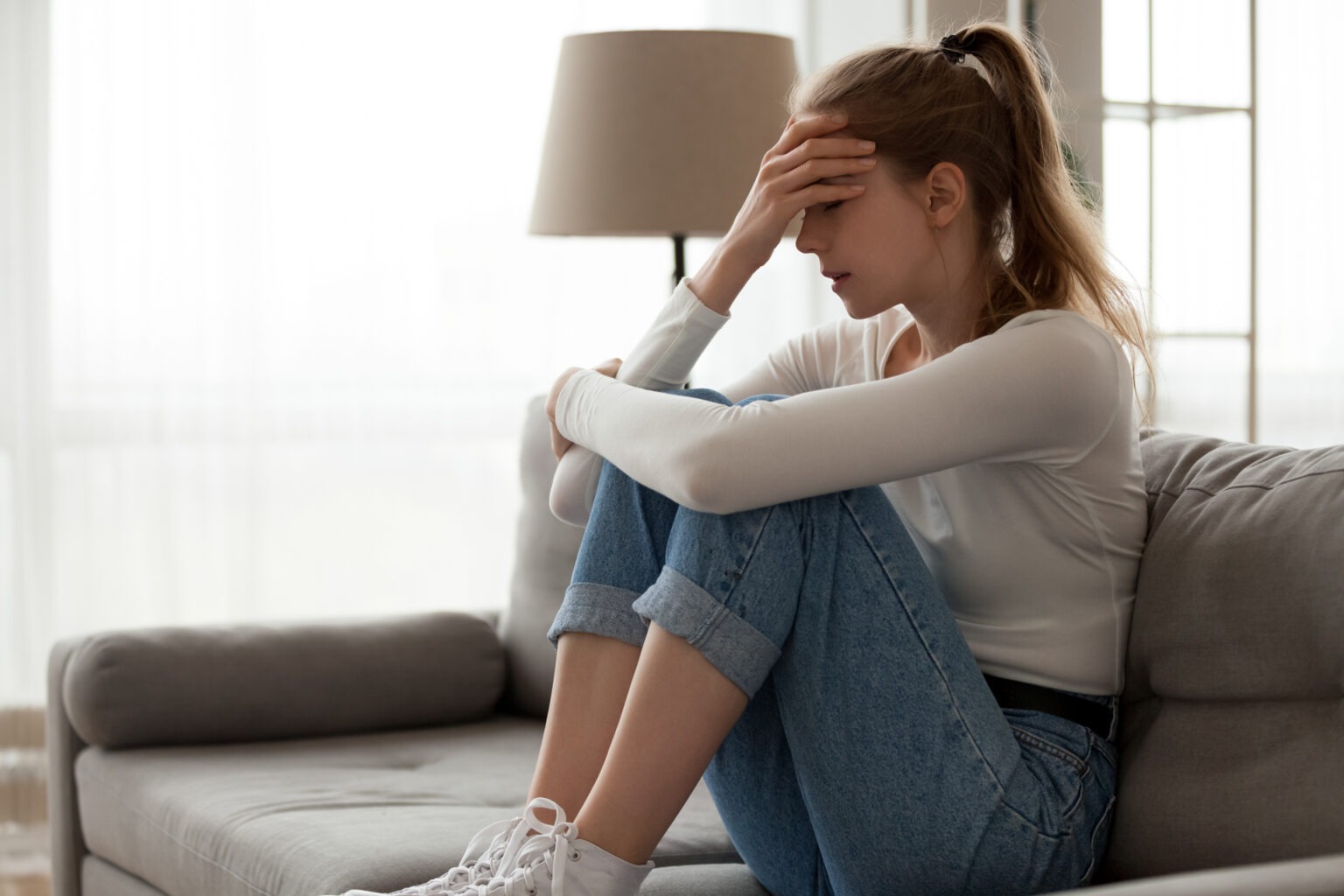 Frustrated woman holding head on couch