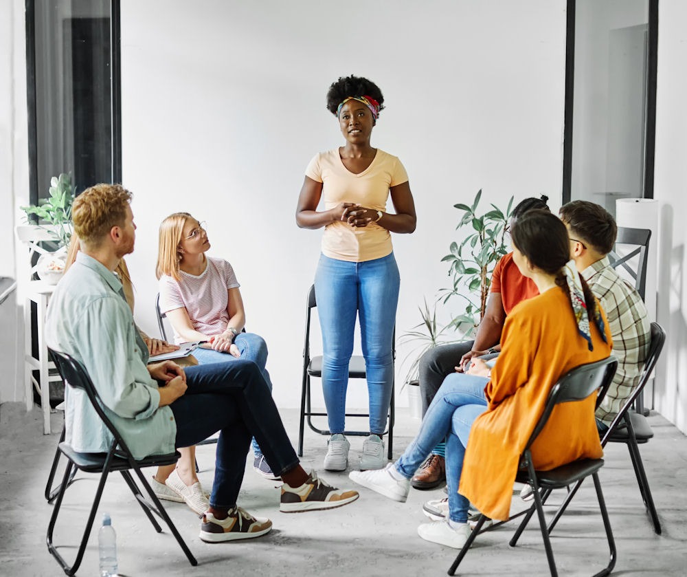 Woman standing to tell story at Cypress Lake Recovery addiction support group