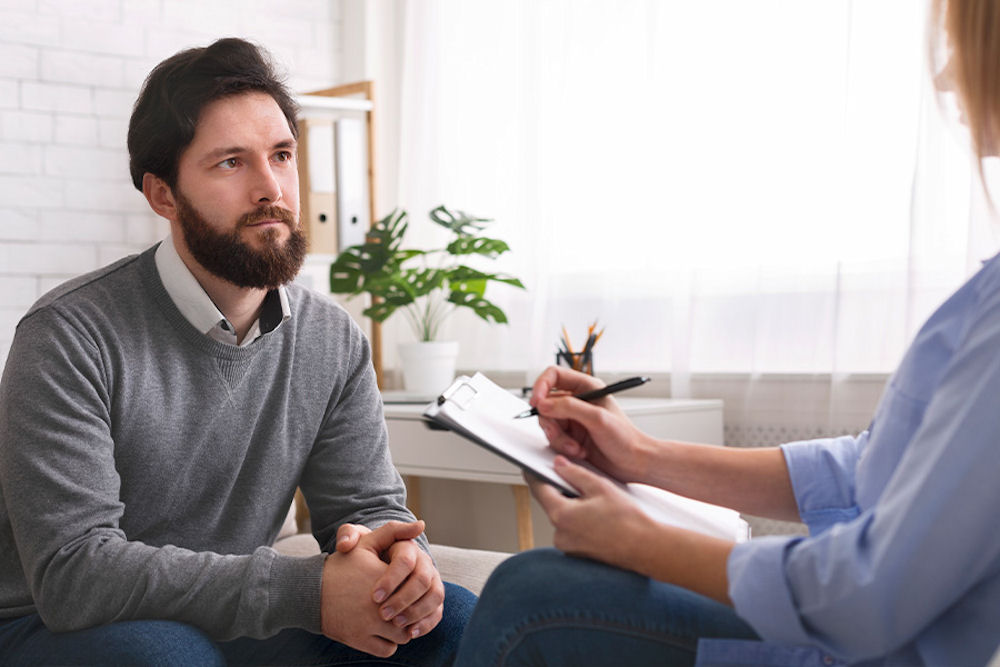 Attentive man receiving instructions from therapist with clipboard.