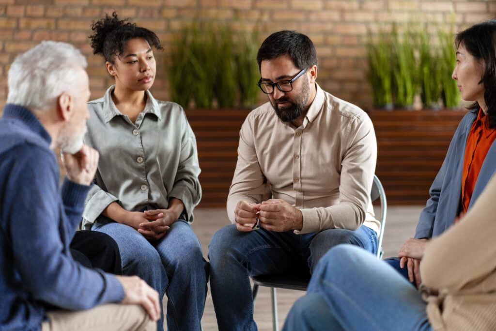 People participating in a supportive 12-step recovery group discussion during addiction treatment