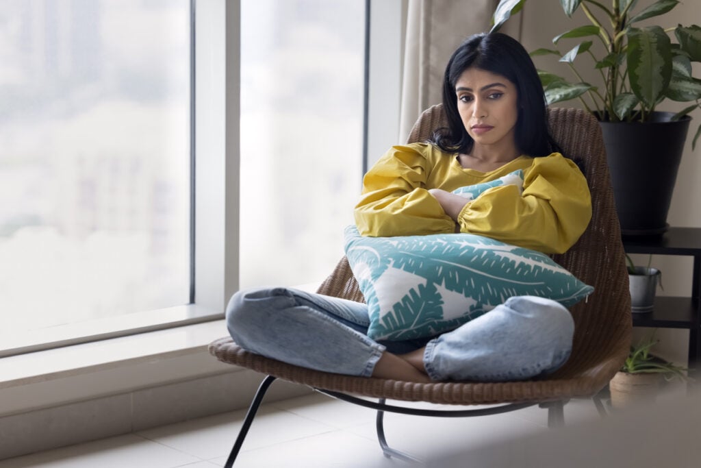 Woman sitting quietly by a window, illustrating fatigue and low mood during Adderall withdrawal.